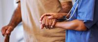help from caregiver or nurse walking with senior man or patient in a nursing home